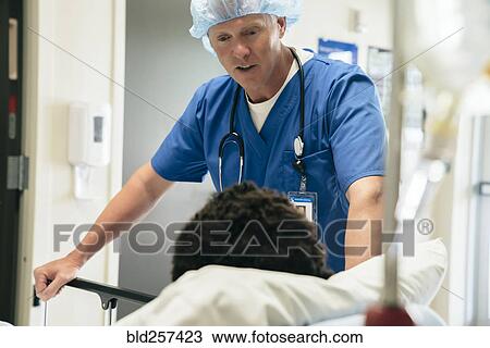 Stock Image - Doctor talking to boy in hospital bed. Fotosearch