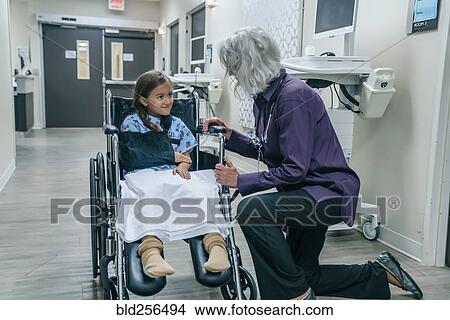 Picture - Doctor talking to girl in a wheelchair. Fotosearch