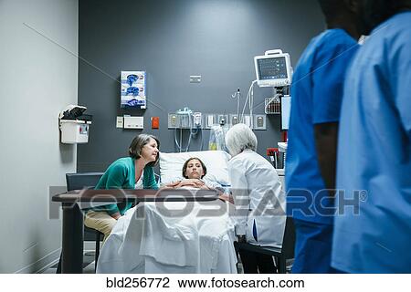 Stock Image - Doctor talking to mother and daughter in hospital. Fotosearch