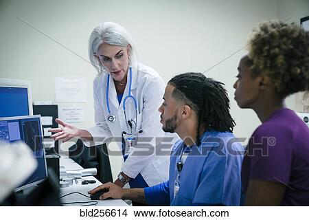 Doctor talking to nurses at computer View Large Photo Image Picture - Doctor talking to nurses at computer. Fotosearch