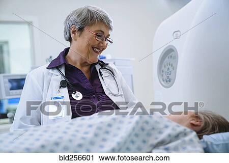 Stock Image - Doctor talking to patient at scanner. Fotosearch