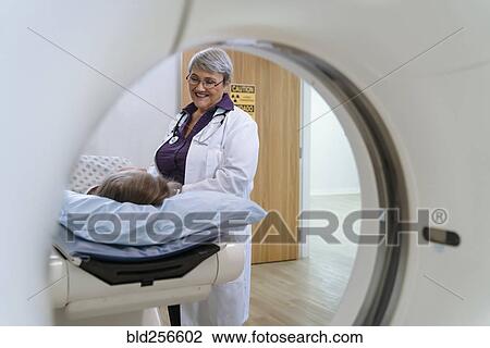 Stock Image - Doctor talking to patient at scanner. Fotosearch