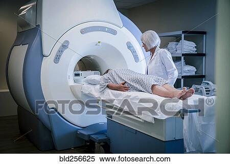 Stock Photography - Doctor talking to patient at scanner. Fotosearch