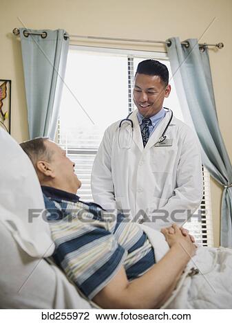 Stock Image - Doctor talking to patient in hospital bed. Fotosearch