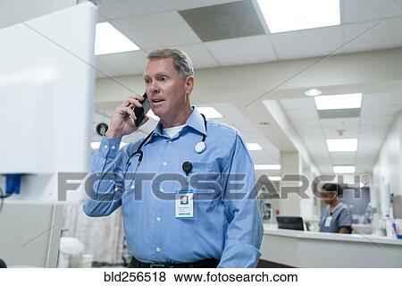 Stock Photo - Doctor using computer and talking on cell phone. Fotosearch