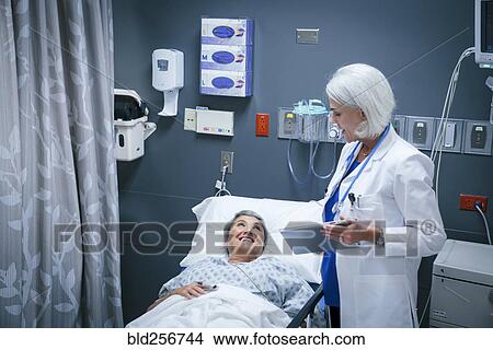 Picture - Doctor with digital tablet talking to smiling patient in hospital. Fotosearch