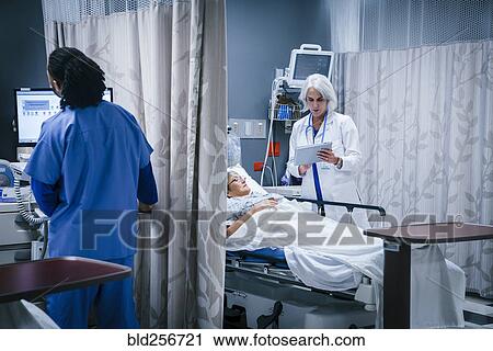 Stock Image - Doctor with digital tablet talking to patient in hospital bed. Fotosearch