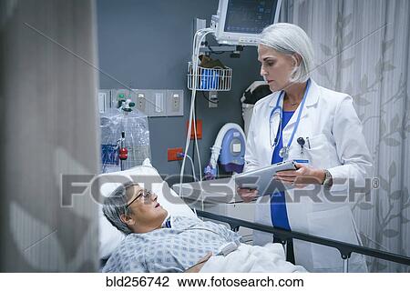Stock Image - Doctor with digital tablet talking to patient. Fotosearch