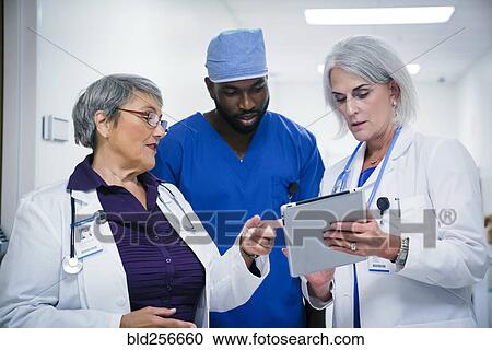 Stock Image - Doctors and nurse discussing digital tablet. Fotosearch