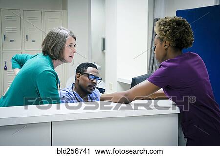 Stock Image - Doctors and nurses talking in hospital. Fotosearch