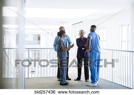 Stock Photograph - Doctors and nurses talking near staircase. Fotosearch