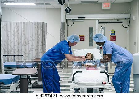 Stock Image - Doctors talking to girl in hospital gurney. Fotosearch