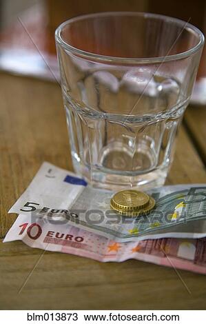 Stock Image - Empty glass and Euro notes and coins. Fotosearch
