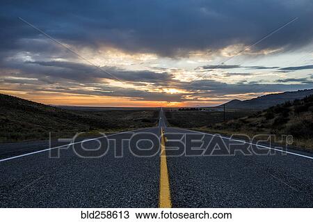 Stock Image - Empty remote road at sunset. Fotosearch