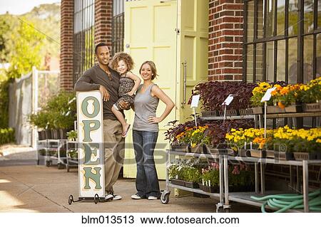 Stock Image - Family standing near florist open sign. Fotosearch