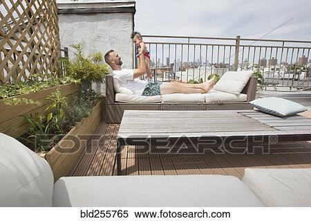 Stock Photography - Father relaxing with baby daughter on patio. Fotosearch