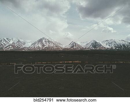 Field near snowy mountain range View Large Photo Image Stock Image - Field near snowy mountain range. Fotosearch