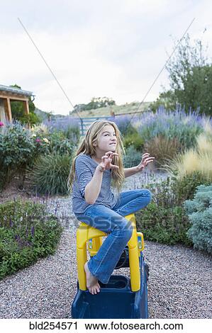 Stock Image - Fierce Caucasian girl sitting on toy car. Fotosearch