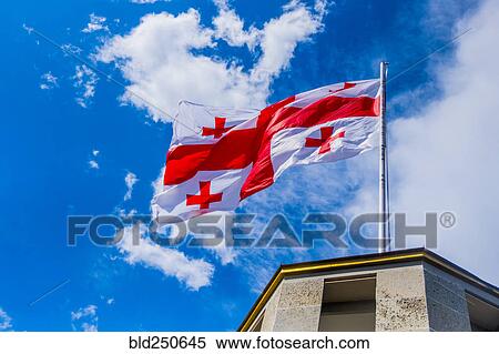 Flag blowing in wind on top of building View Large Photo Image Stock Photography - Flag blowing in wind on top of building. Fotosearch