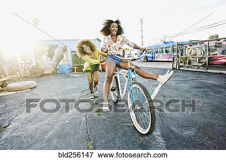 Friend pushing carefree woman on bicycle View Large Photo Image Stock Photo - Friend pushing carefree woman on bicycle. Fotosearch
