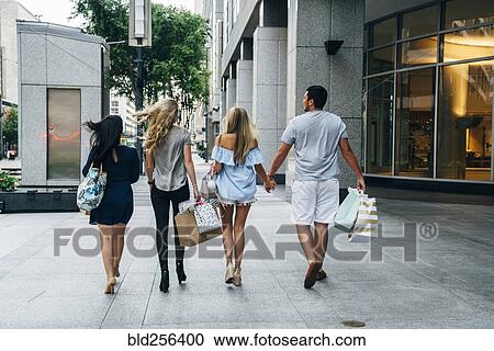 Stock Image - Friends carrying shopping bags in city. Fotosearch