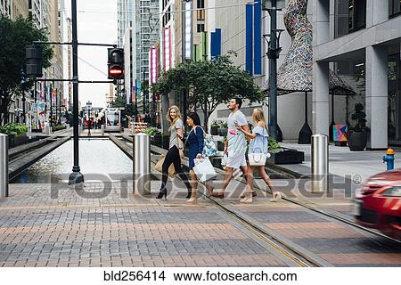 Friends crossing street in city carrying shopping bags View Large Photo Image Picture - Friends crossing street in city carrying shopping bags. Fotosearch
