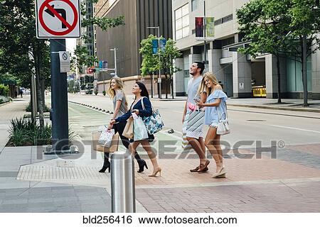 Friends crossing street in city carrying shopping bags View Large Photo Image Stock Photograph - Friends crossing street in city carrying shopping bags. Fotosearch