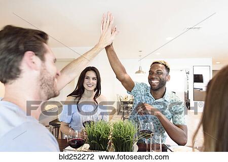 Stock Image - Friends drinking red wine and high-fiving. Fotosearch