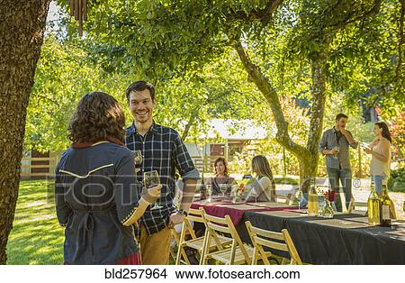 Picture - Friends drinking wine at party outdoors. Fotosearch
