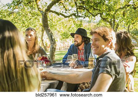 Stock Image - Friends drinking wine at party outdoors. Fotosearch