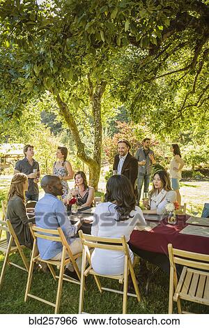 Stock Photograph - Friends drinking wine at party outdoors. Fotosearch