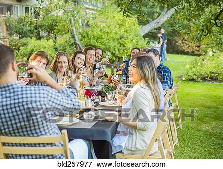 Stock Photo - Friends enjoying wine at party outdoors. Fotosearch