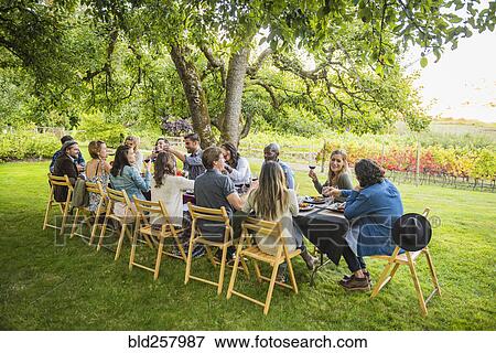 Stock Photo - Friends enjoying wine at party outdoors. Fotosearch