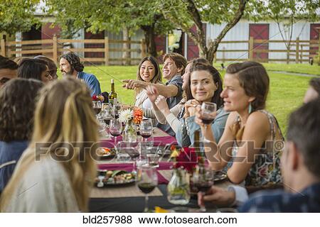 Stock Photo - Friends enjoying wine at party outdoors. Fotosearch