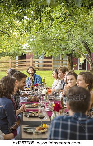Stock Photo - Friends enjoying wine at party outdoors. Fotosearch
