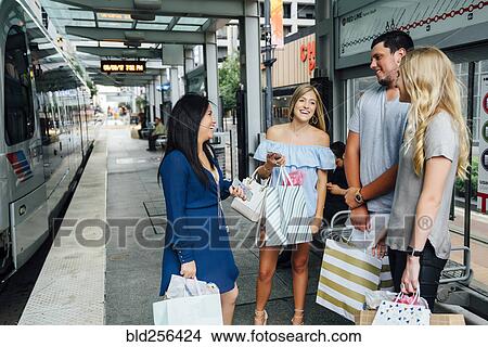 Friends laughing and talking at train station View Large Photo Image Picture - Friends laughing and talking at train station. Fotosearch