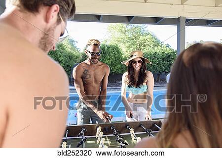 Friends playing foosball outdoors near swimming pool View Large Photo Image Stock Image - Friends playing foosball outdoors near swimming pool. Fotosearch