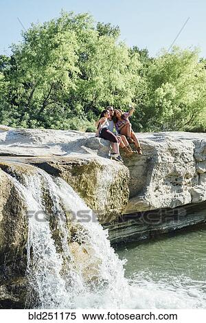 Friends posing for cell phone selfie on rocks near waterfall View Large Photo Image Stock Photography - Friends posing for cell phone selfie on rocks near waterfall. Fotosearch