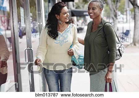 Stock Photo - Friends shopping together in city. Fotosearch