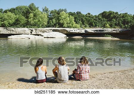 Stock Photography - Friends sitting near river. Fotosearch