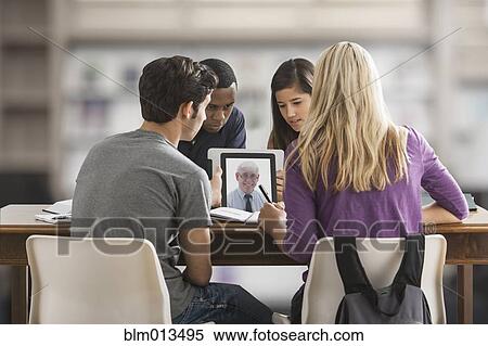 Stock Photography - Friends studying together using digital tablet. Fotosearch