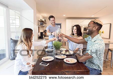 Stock Photography - Friends toasting with champagne at table. Fotosearch