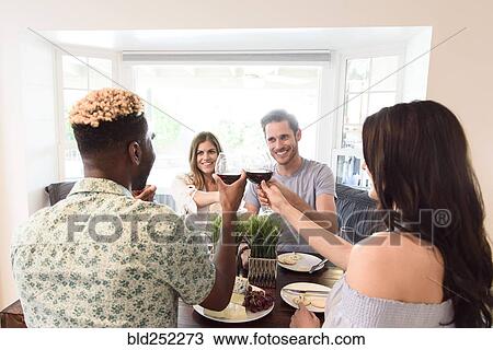 Friends toasting with red wine at table View Large Photo Image Stock Image - Friends toasting with red wine at table. Fotosearch