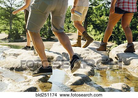 Picture - Friends walking on rocks near river. Fotosearch