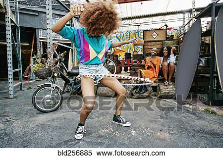 Stock Photography - Friends watching woman spinning hoop around thighs. Fotosearch
