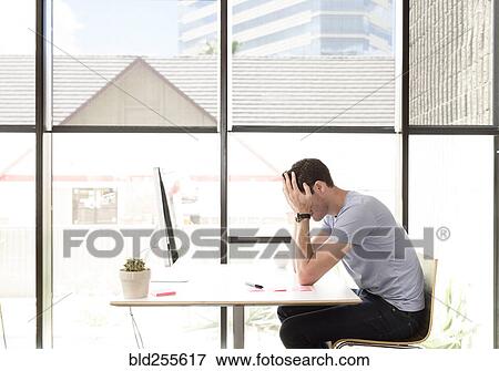 Frustrated Caucasian man with head in hands at desk View Large Photo Image Stock Photo - Frustrated Caucasian man with head in hands at desk. Fotosearch