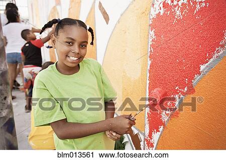 Stock Image - Girl painting wall. Fotosearch