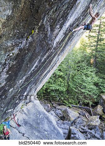 Stock Image - Girl watching boy climbing rock. Fotosearch