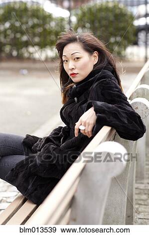 Stock Photo - Glamorous Korean woman sitting on bench. Fotosearch