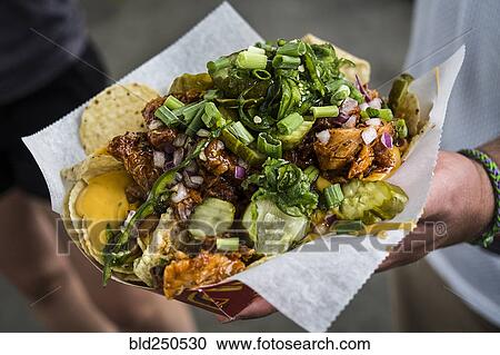 Stock Image - Hand holding loaded nachos. Fotosearch